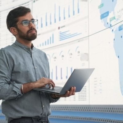 stock-photo-indian-male-logistics-expert-holding-laptop-computer-and-analyzing-world-map-on-big-digital-screen-2348534845-transformed (1)